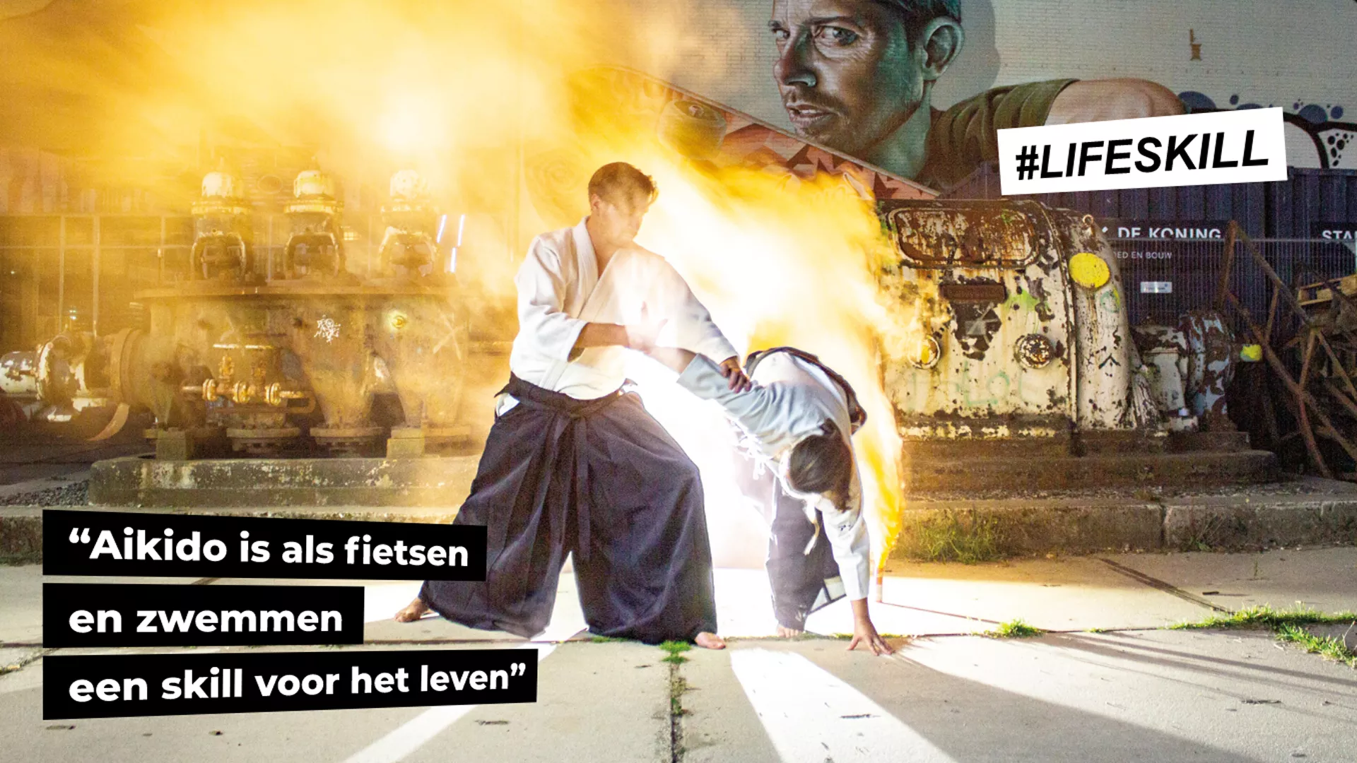 sensei edo maakt een ikkyo beweging bij anne slui als uke. voor een graffiti muur bij Strijp-s dit beeld is spectaculair door de belichting en rook die een mooi effect geeft